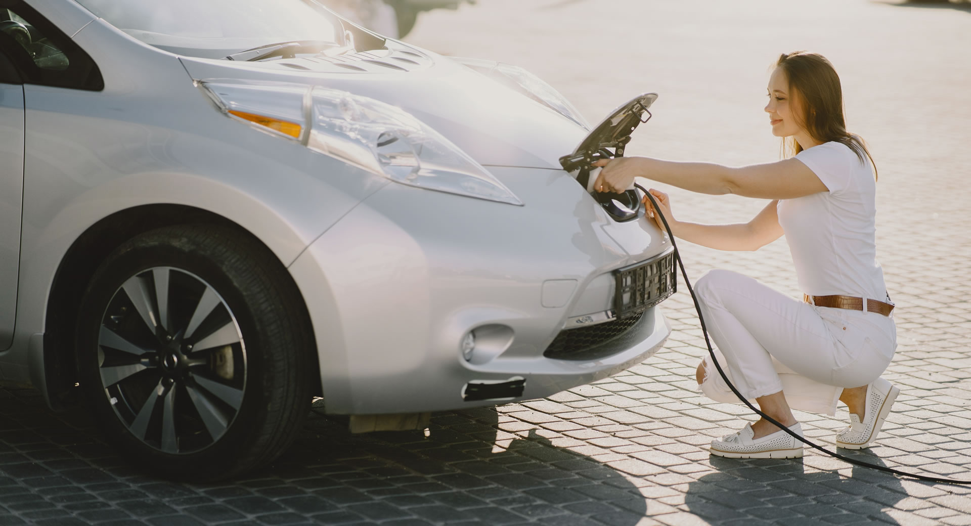 Person plugging a charging cable into an electric car